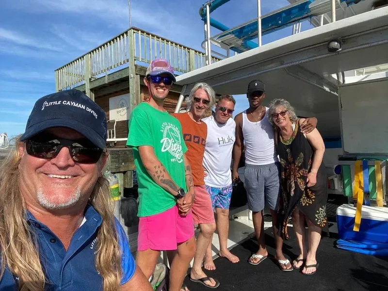 Groupe de plongeurs souriants posant devant un bateau de plongée