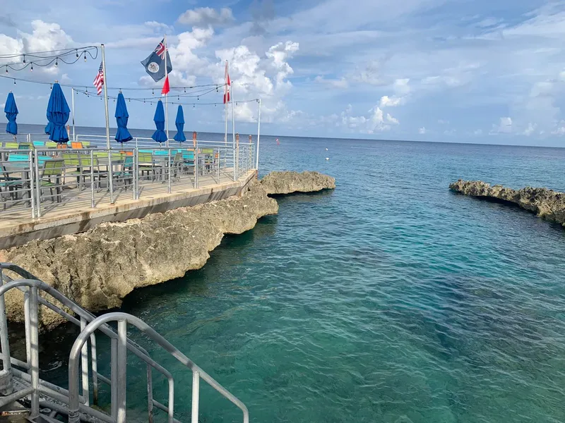 Terrasse avec parasols, vue sur la mer turquoise et rochers