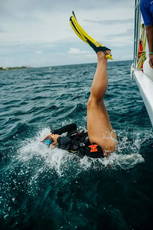 Plongeur entrant dans l'eau depuis un bateau, jambes en l'air