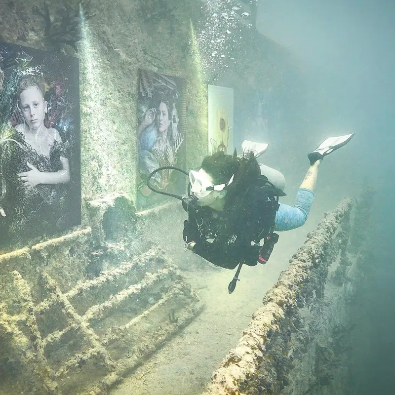 Plongeur explore une structure sous-marine avec des portraits encadrés