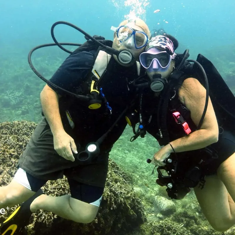 Deux plongeurs souriants se regardent sous l'eau avec leur équipement