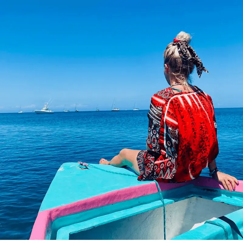 Une personne assise à l'avant d'un bateau sur une mer bleue