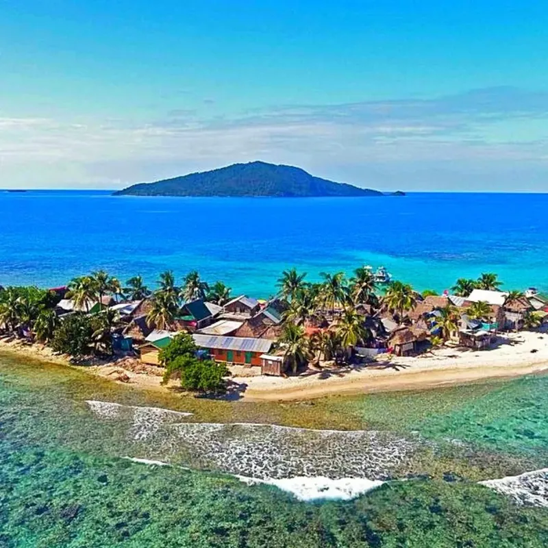 Vue aérienne d'un village côtier tropical avec des bateaux et végétation