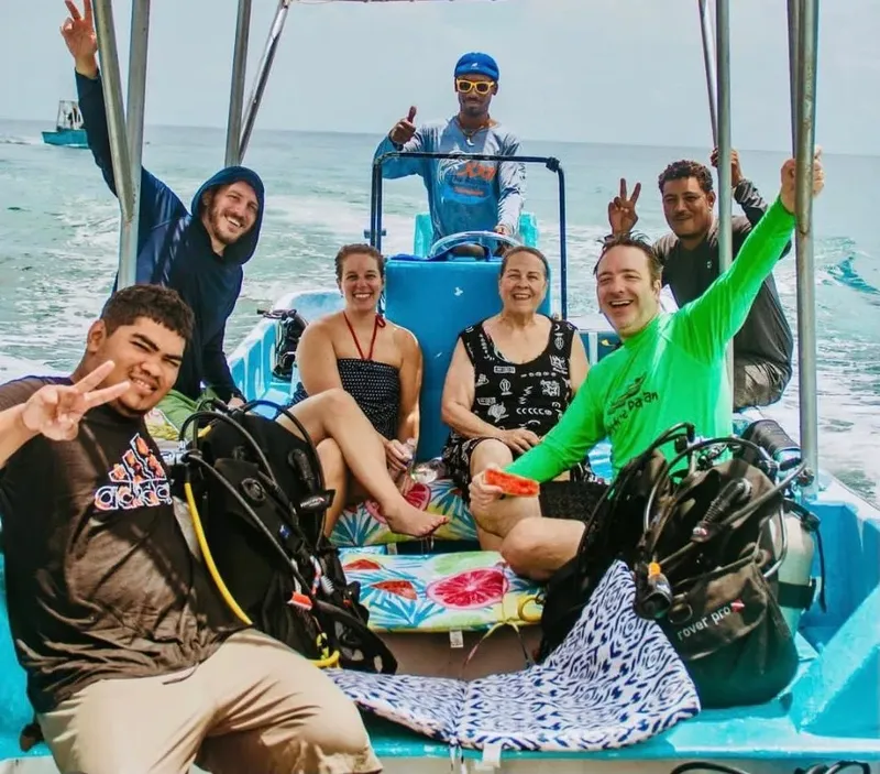 Groupe de plongeurs souriants sur un bateau bleu en mer