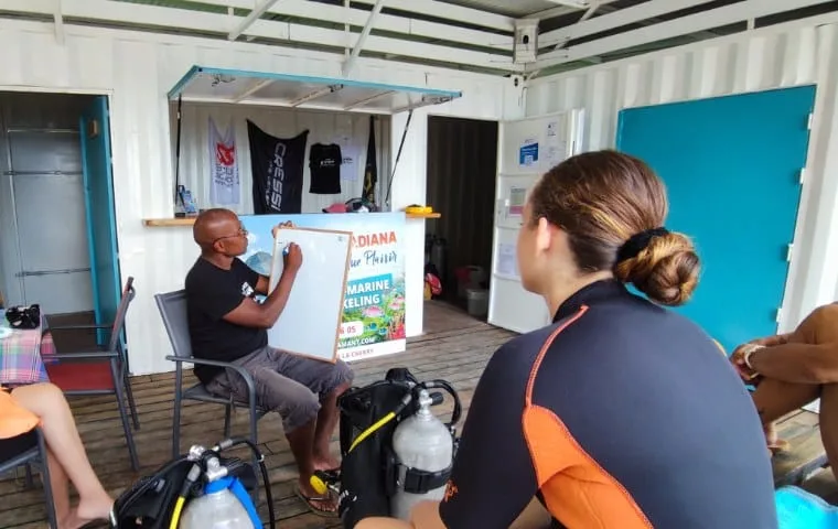 Instructeur expliquant un plan de plongée à des élèves équipés