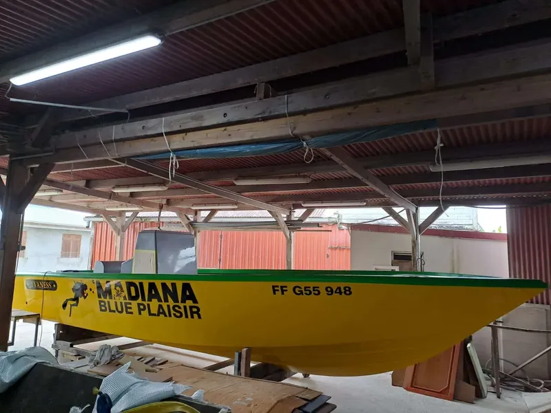 Bateau de plongée jaune et vert sous un abri, vue latérale