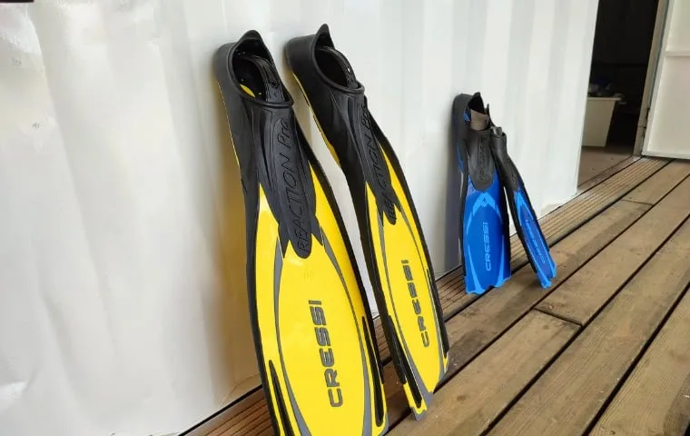 Trois paires de palmes de plongée adossées à un mur extérieur