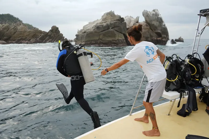 Plongeur s'apprête à sauter d'un bateau avec assistance d'un moniteur