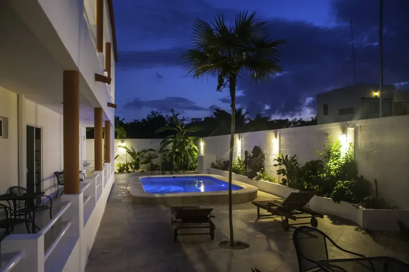 Cour intérieure avec piscine et végétation tropicale éclairée le soir