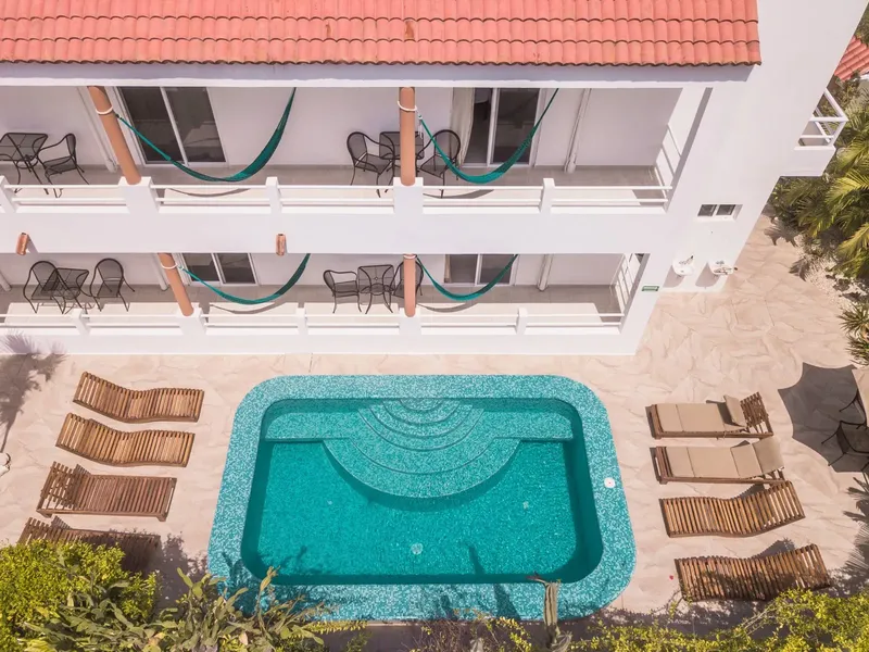 Vue aérienne d'une piscine et d'une maison blanche avec des hamacs