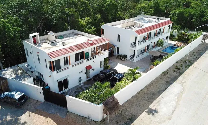 Vue aérienne de bâtiments blancs avec piscine et végétation tropicale