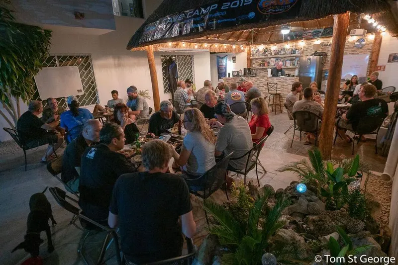 Groupe de personnes assises autour de tables dans un espace extérieur éclairé