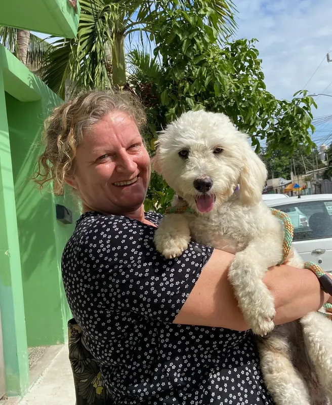 Femme souriante tenant un chien blanc et duveteux dans ses bras