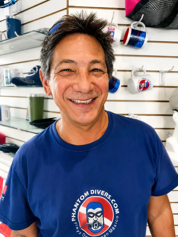 Homme souriant dans un magasin de plongée avec du matériel autour