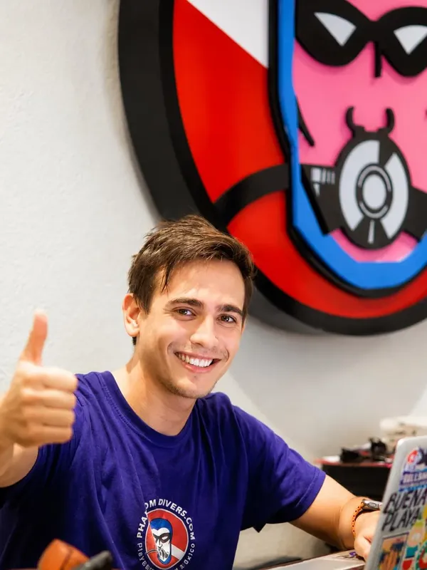 Jeune homme souriant, pouce levé, devant une décoration murale colorée