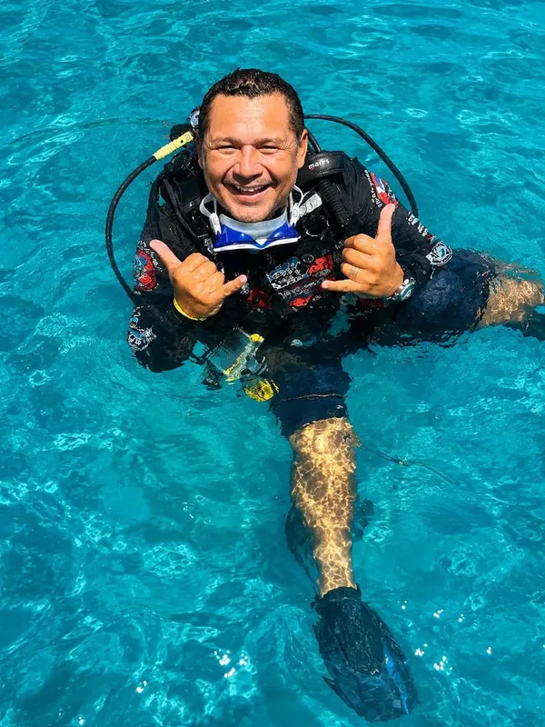 Plongeur souriant dans l'eau avec signe de validation et équipement