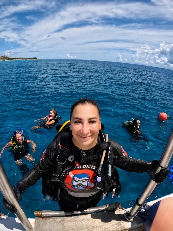 Plongeuse souriante sur un bateau avec d'autres plongeurs en mer