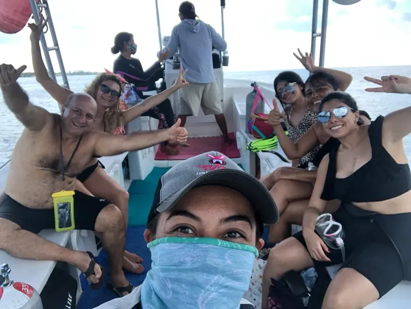 Groupe de personnes souriantes sur un bateau en mer, signe de la main