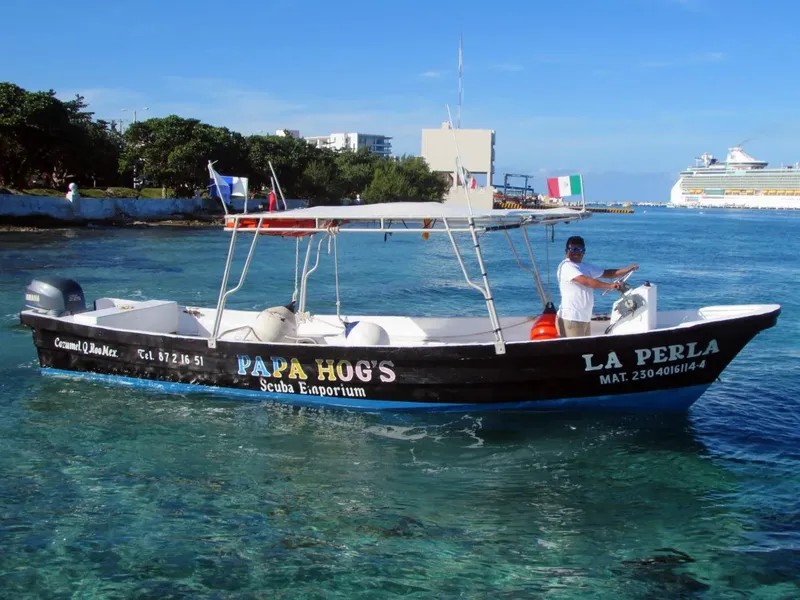 Bateau de plongée navigue sur une eau turquoise ensoleillée avec un pilote