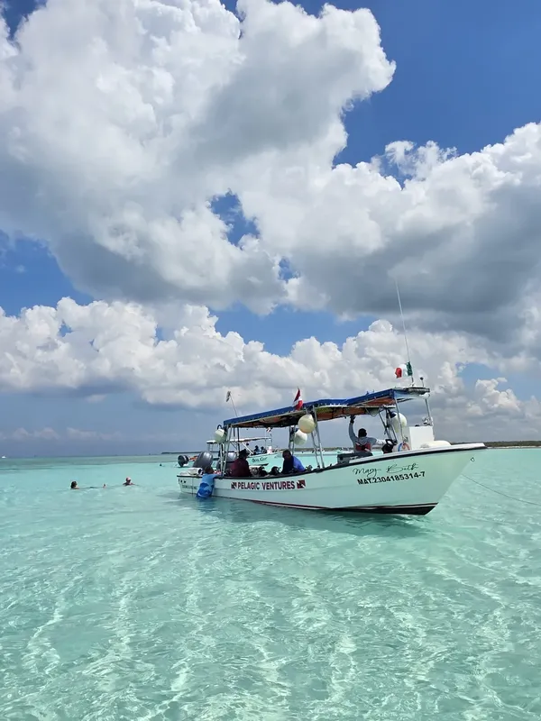 Bateau de plongée sur une eau turquoise claire sous un ciel nuageux