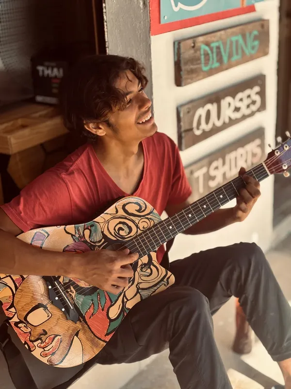 Un homme souriant joue de la guitare dans un centre de plongée