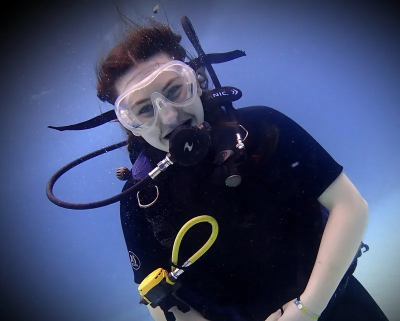 Plongeuse souriante avec masque et détendeur sous l'eau bleue