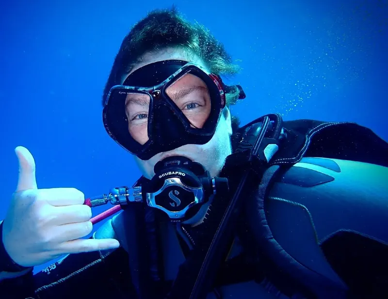 Plongeur souriant avec signe de validation, immersion en bleu profond