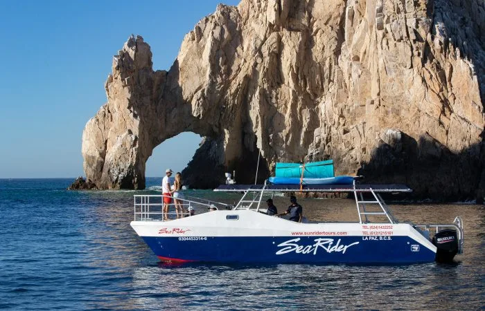Bateau de plongée blanc et bleu amarré devant une formation rocheuse