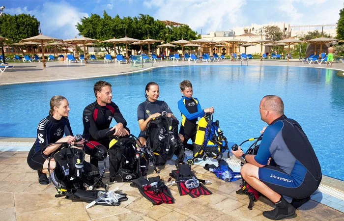 Groupe de plongeurs équipés près d'une piscine ensoleillée