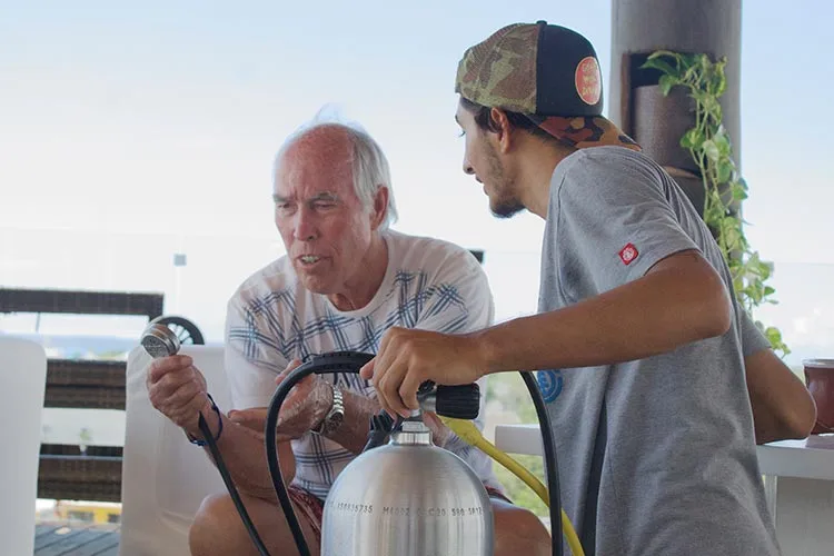 Deux hommes discutent autour d'une bouteille de plongée, préparation