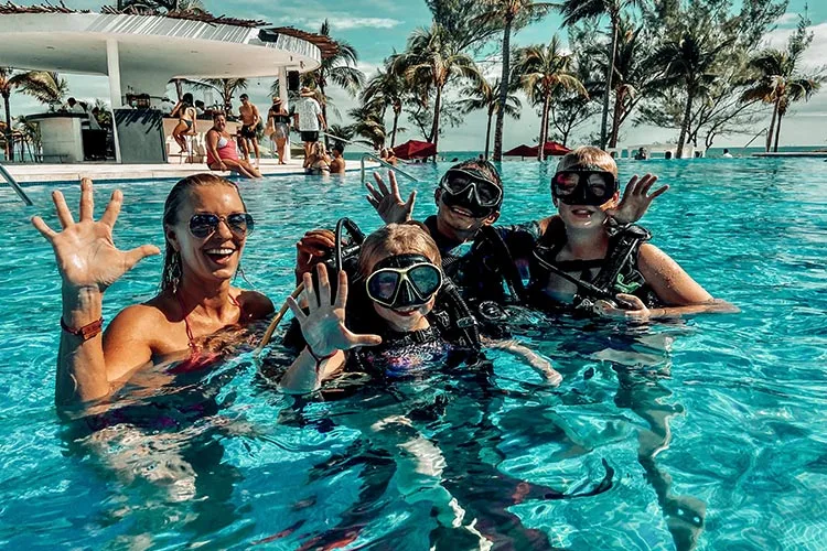 Groupe de personnes souriantes en équipement de plongée dans une piscine