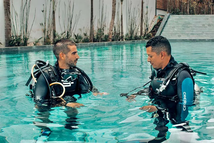 Deux plongeurs en combinaison discutent dans une piscine claire
