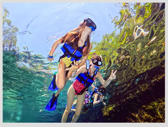 Trois personnes en maillot de bain font du snorkeling en mer