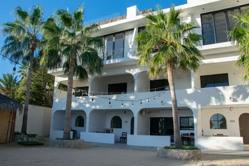 Bâtiment blanc à deux étages avec des arches et des palmiers