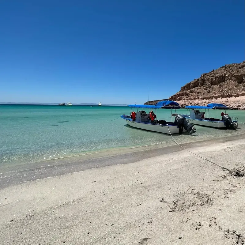 Plage de sable clair avec deux bateaux de plongée et des personnes