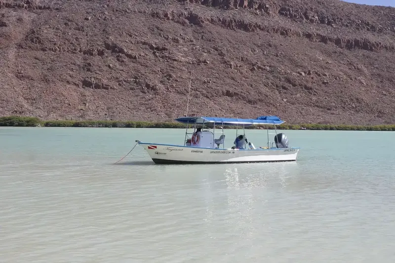 Bateau de plongée amarré dans une eau turquoise avec des passagers