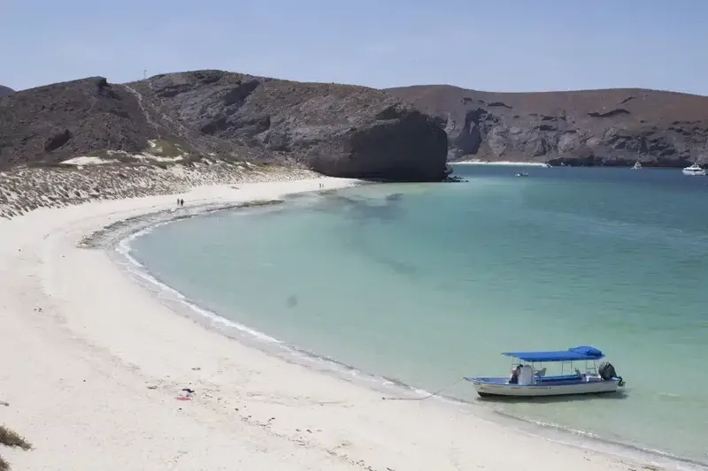 Plage de sable blanc avec un petit bateau et des personnes