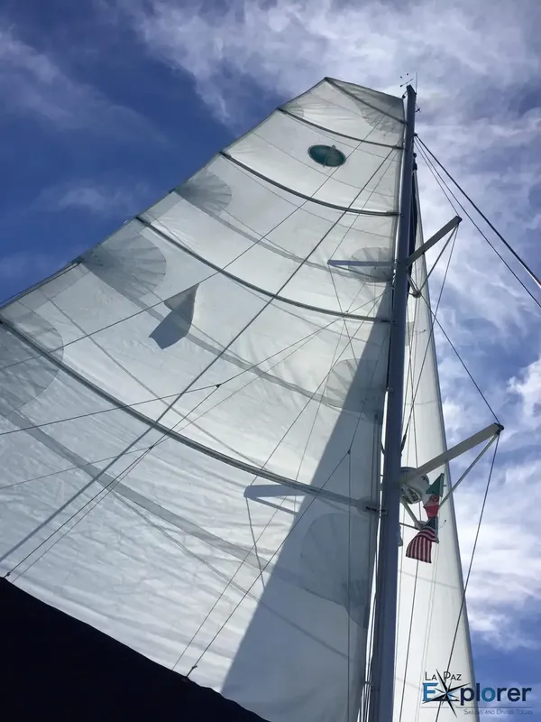 Voilier avec ses voiles blanches contre un ciel nuageux et drapeaux