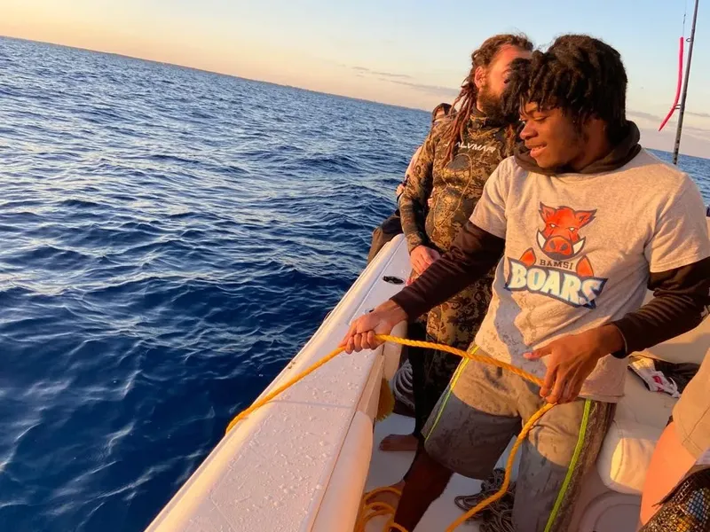 Deux hommes sur un bateau en mer, manipulant une corde jaune