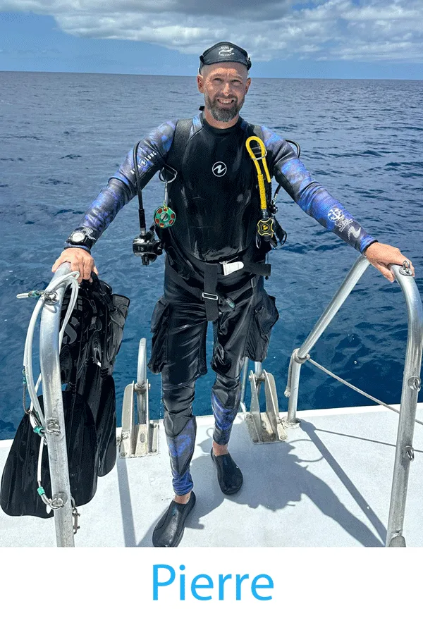Plongeur souriant en combinaison complète sur le pont d'un bateau