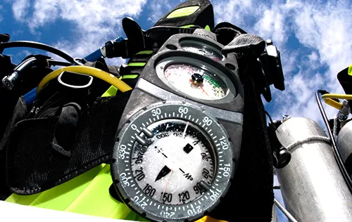 Equipement de plongée avec manomètre, boussole et détendeur contre ciel bleu