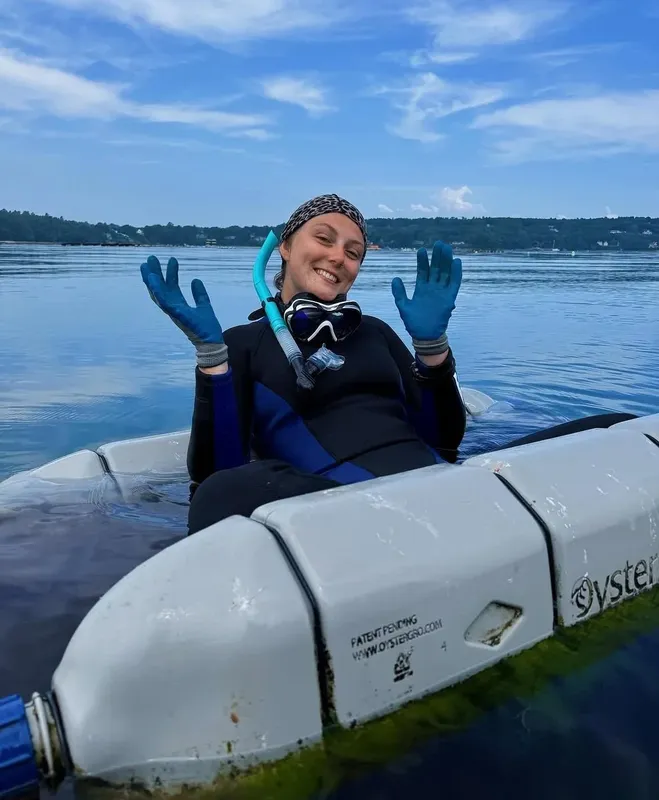 Plongeuse souriante avec masque et tuba, bras levés sur l'eau