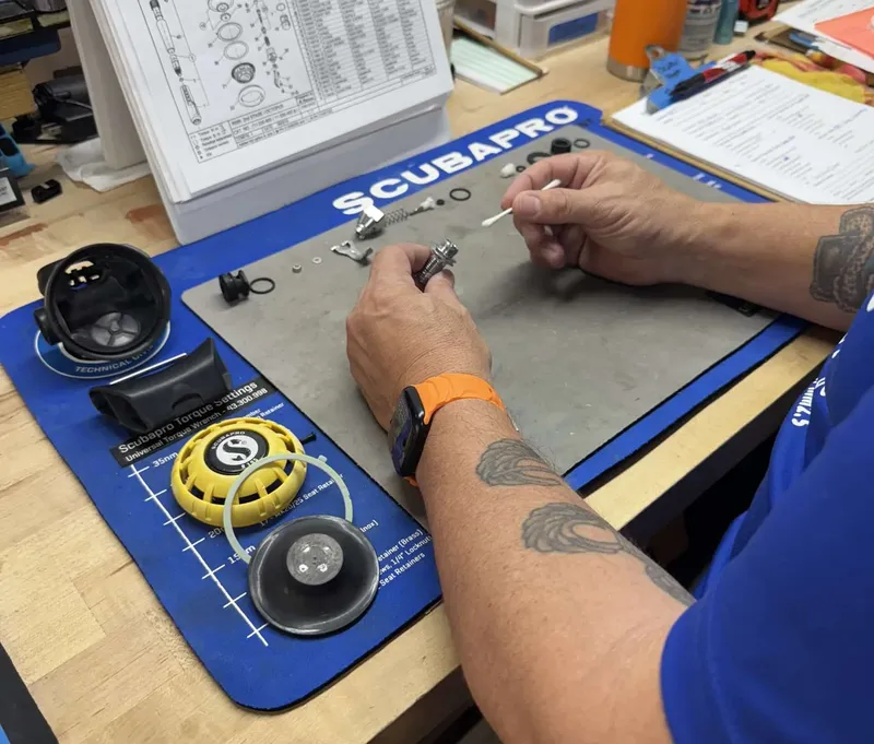 Technicien répare un détendeur Scubapro sur un établi bleu