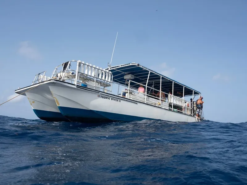 Bateau de plongée blanc avec des passagers, vue depuis la mer