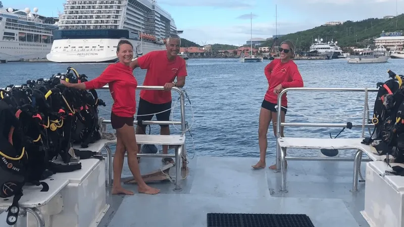 Trois personnes souriantes sur un bateau de plongée avec équipement