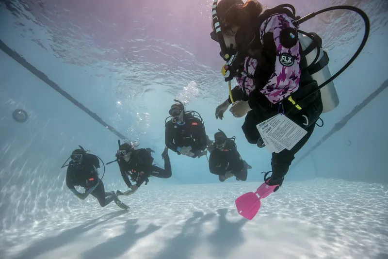 Plongeurs en formation sous-marine, équipés, dans une piscine claire