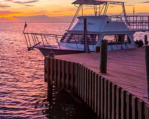 Bateau de plongée amarré à un ponton au coucher du soleil sur l'eau