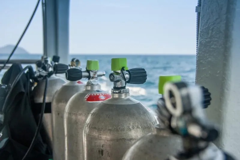 Bouteilles de plongée alignées sur un bateau avec vue sur la mer