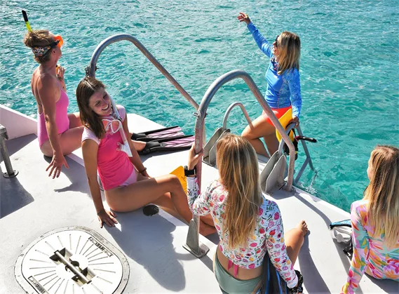Groupe de plongeuses souriantes sur le pont d'un bateau en mer