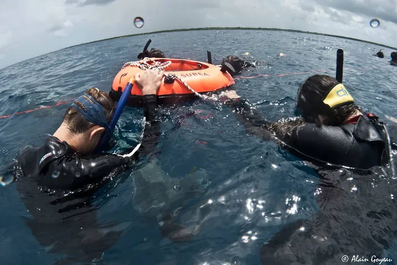 Deux plongeurs flottent à la surface avec un bouée de signalisation orange